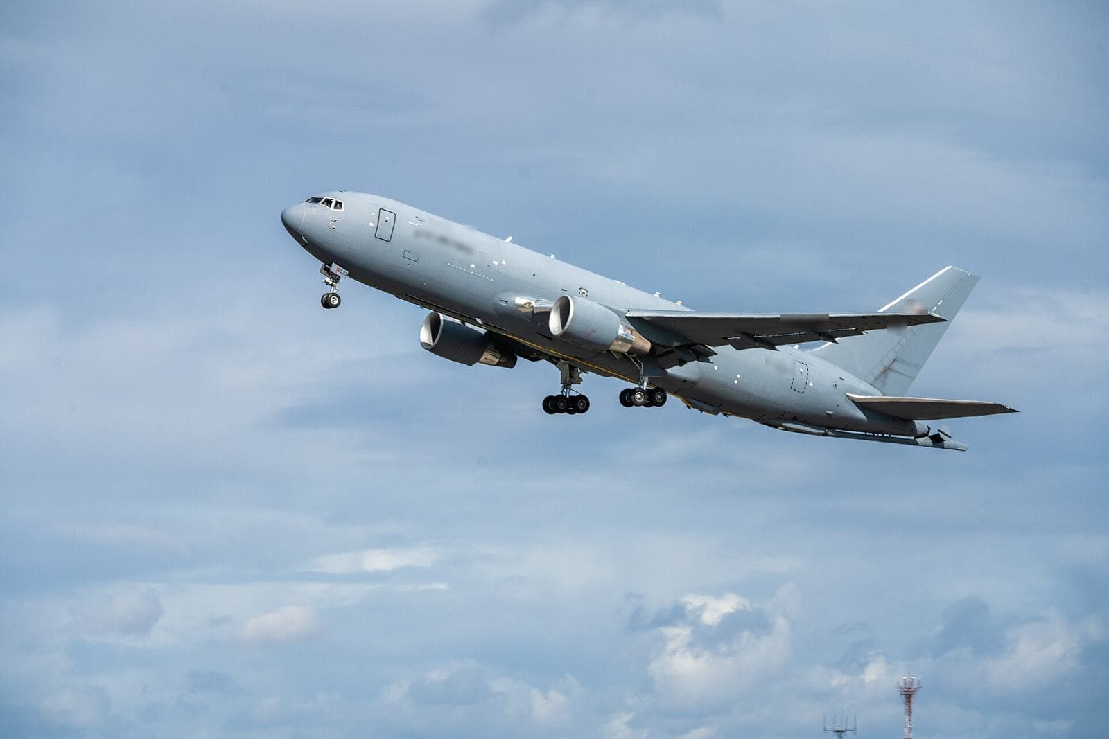 Grey twin-engine jet climbing after take-off against a cloudy sky