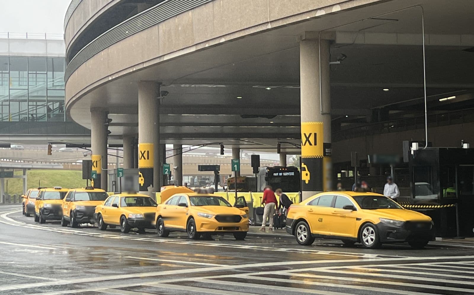 Taxis jaunes alignés à la station de taxis d'un terminal d'aéroport par un jour de pluie